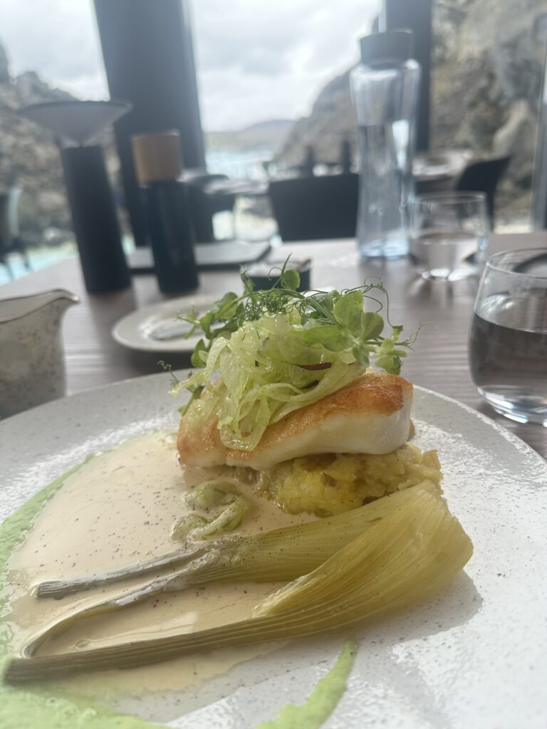 cooked cod filet with over sauce and covered in fresh greens