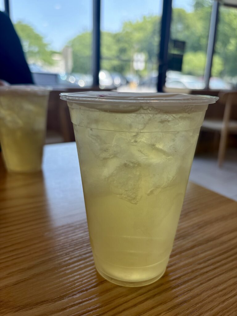 Camellia oolong tea with ice in a plastic cup on top of a wooden table. 