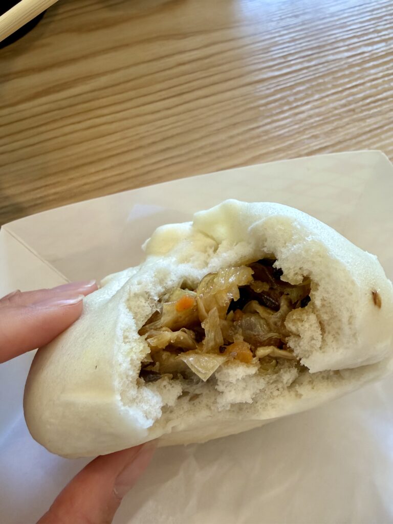 Bao bun with a bite taken out of it exposing the vegetable filling inside. 